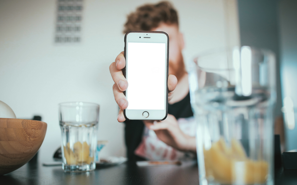 Mobile Mockup: person showing iphone in the coffee shop
