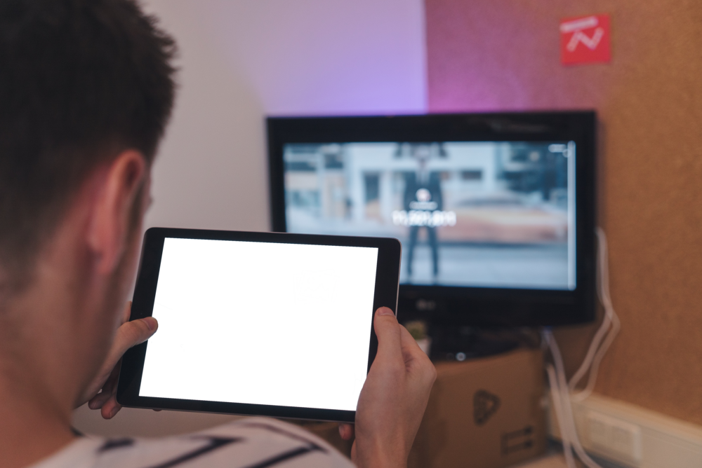 Tablet Mockup: man holding tablet in front of tv